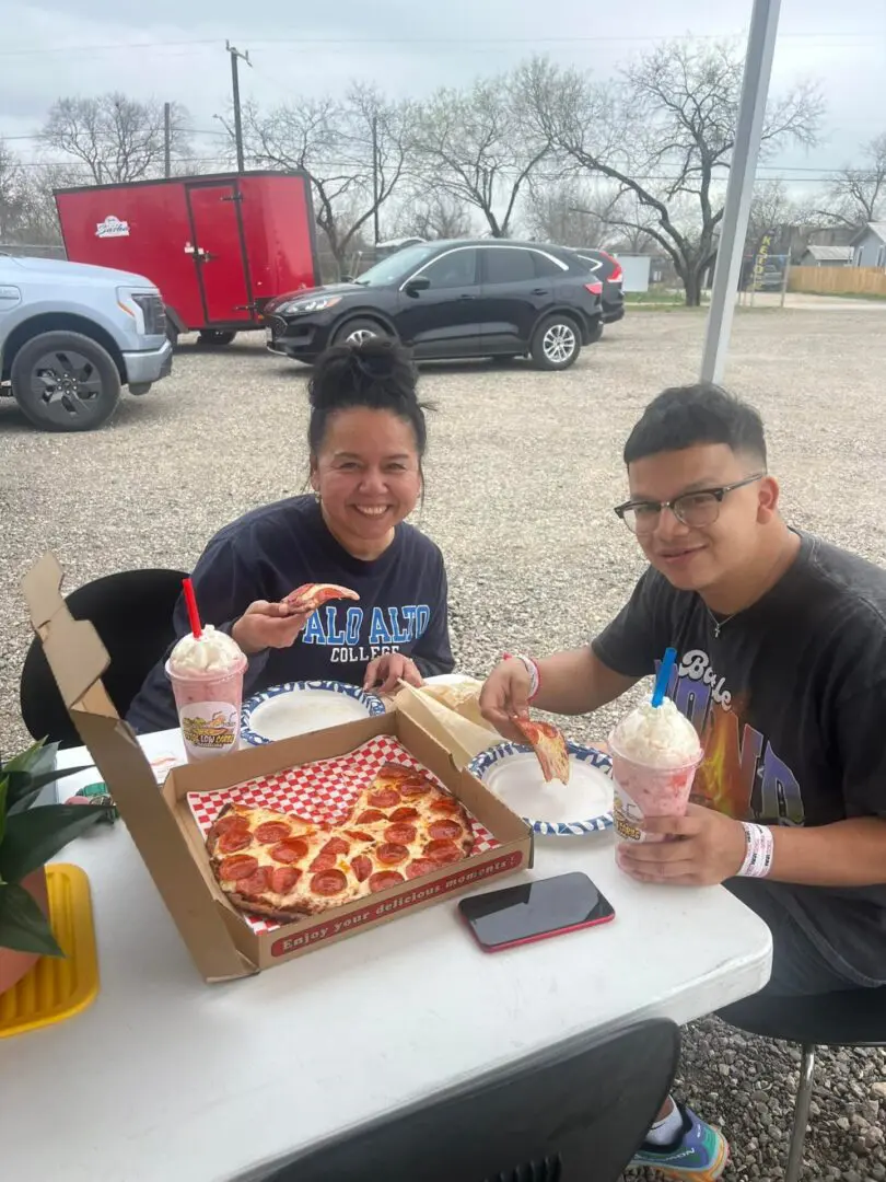 People enjoying pizza and milkshakes outdoors.
