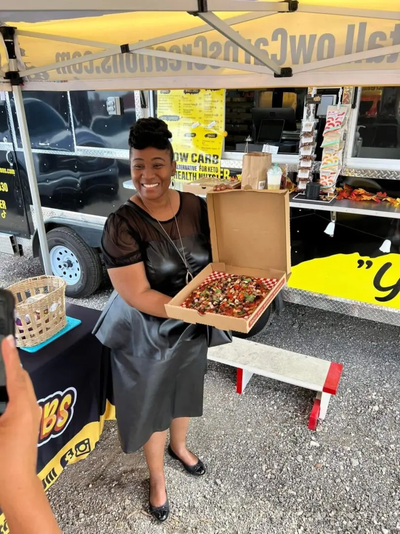 Woman holding a box of colorful pastries.