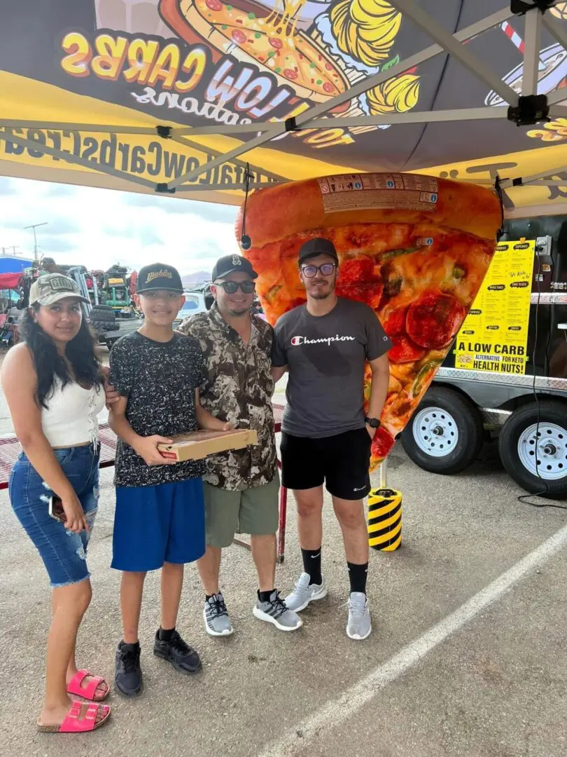 Group posing under pizza-themed tent.