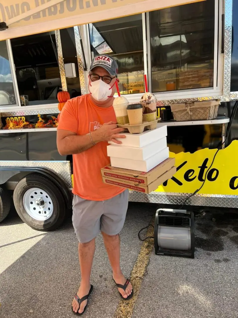 Man carrying food boxes outside food truck.